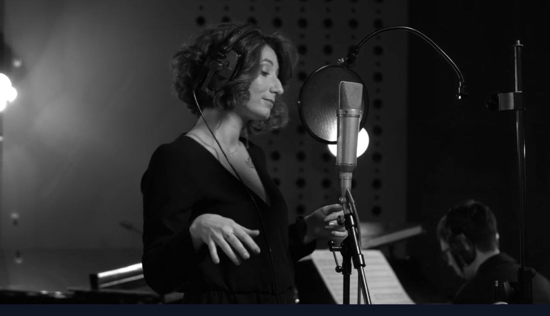 Yana Litinskaya singing at a studio microphone during a group course session