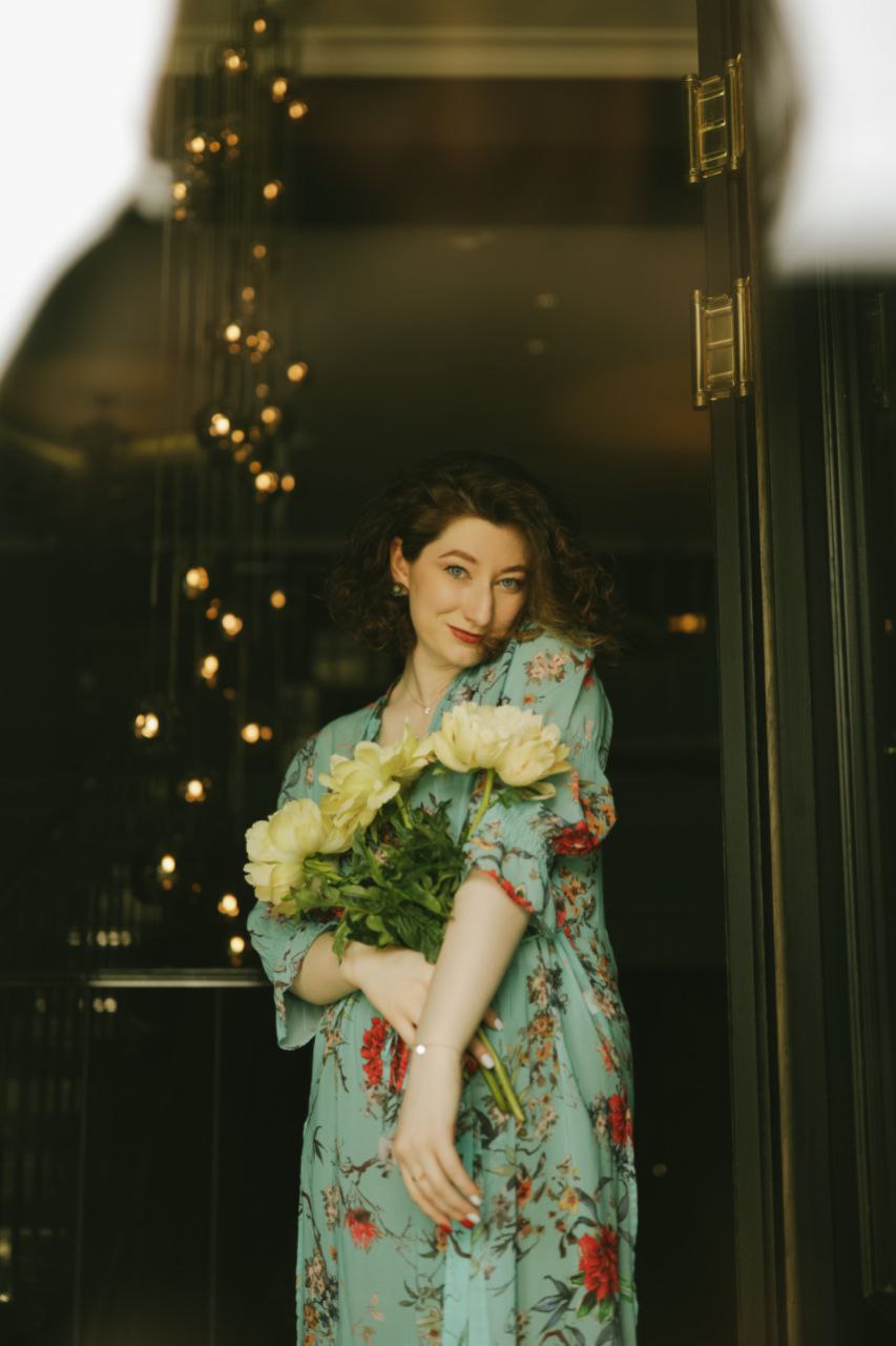 Yana Litinskaya holding peonies in a doorway